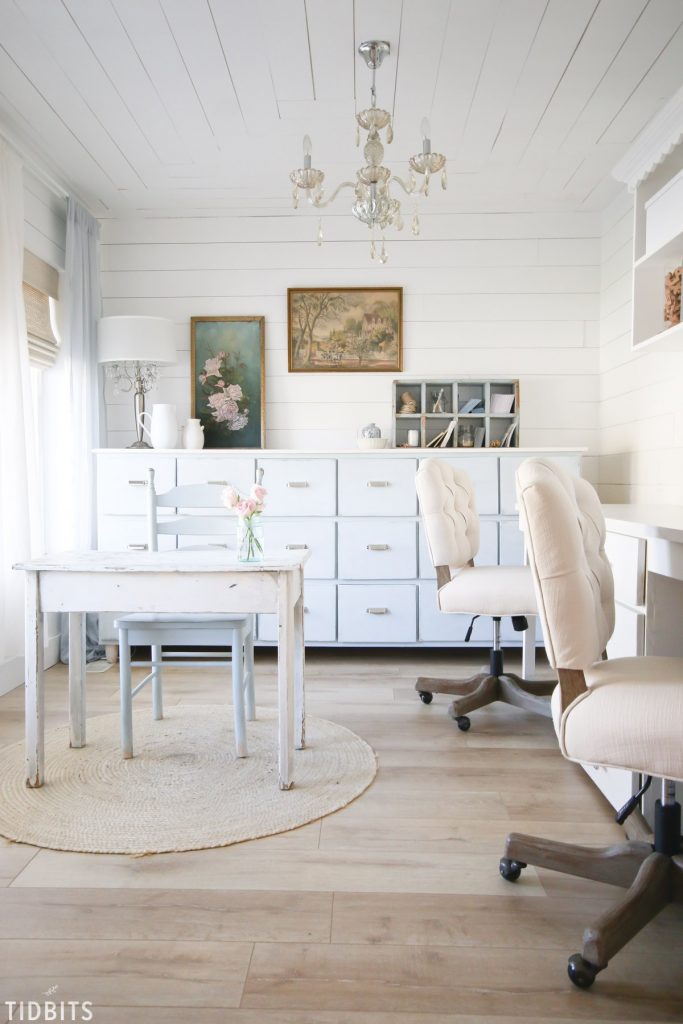 The chandelier in this charming farmhouse office space compliments the rustic wood desk. 