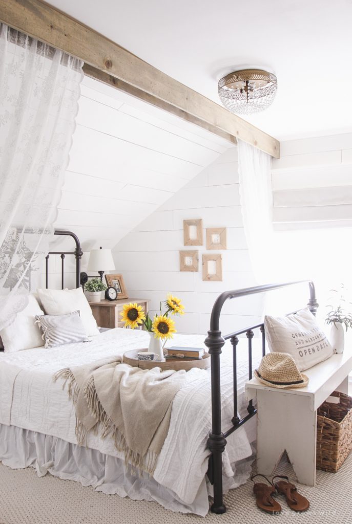 This large wood exposed panel with lace curtains makes this farmhouse room cozy.
