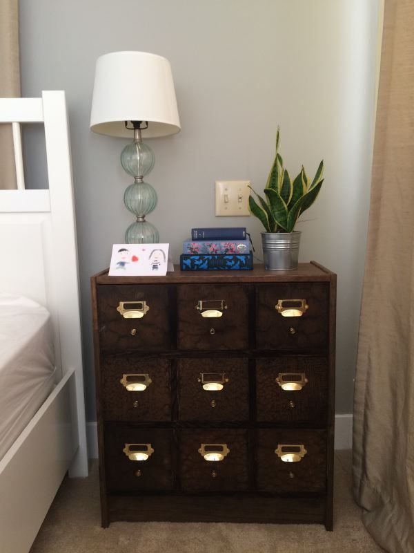 This wood apothecary tables with gold accents works great as a nightstand. 