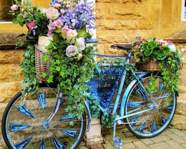 This vintage blue bike with fresh flowers throughout is colorful and fun.
