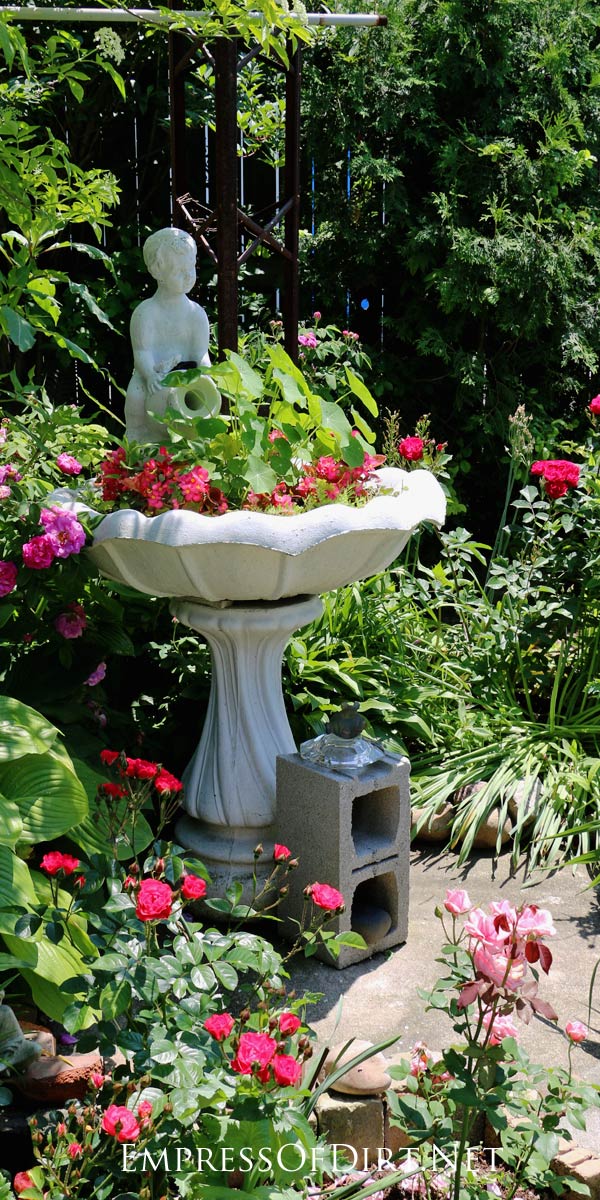 This vintage bird bath with fresh pink flowers is charming in the garden.