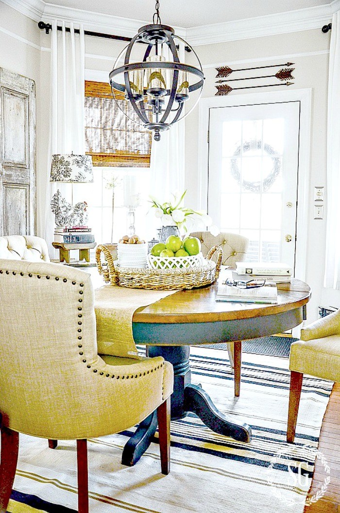 the farmhouse home decor elements in this room come from the centerpiece and arrows above the door