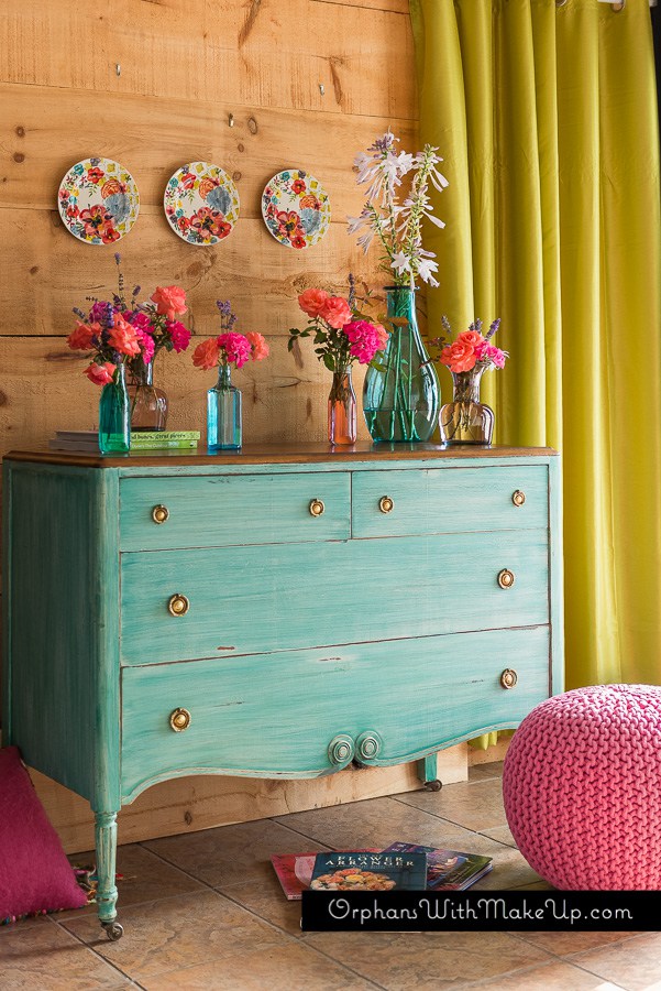 This bright turquoise dresser is color full and compliments the pink floral decor.